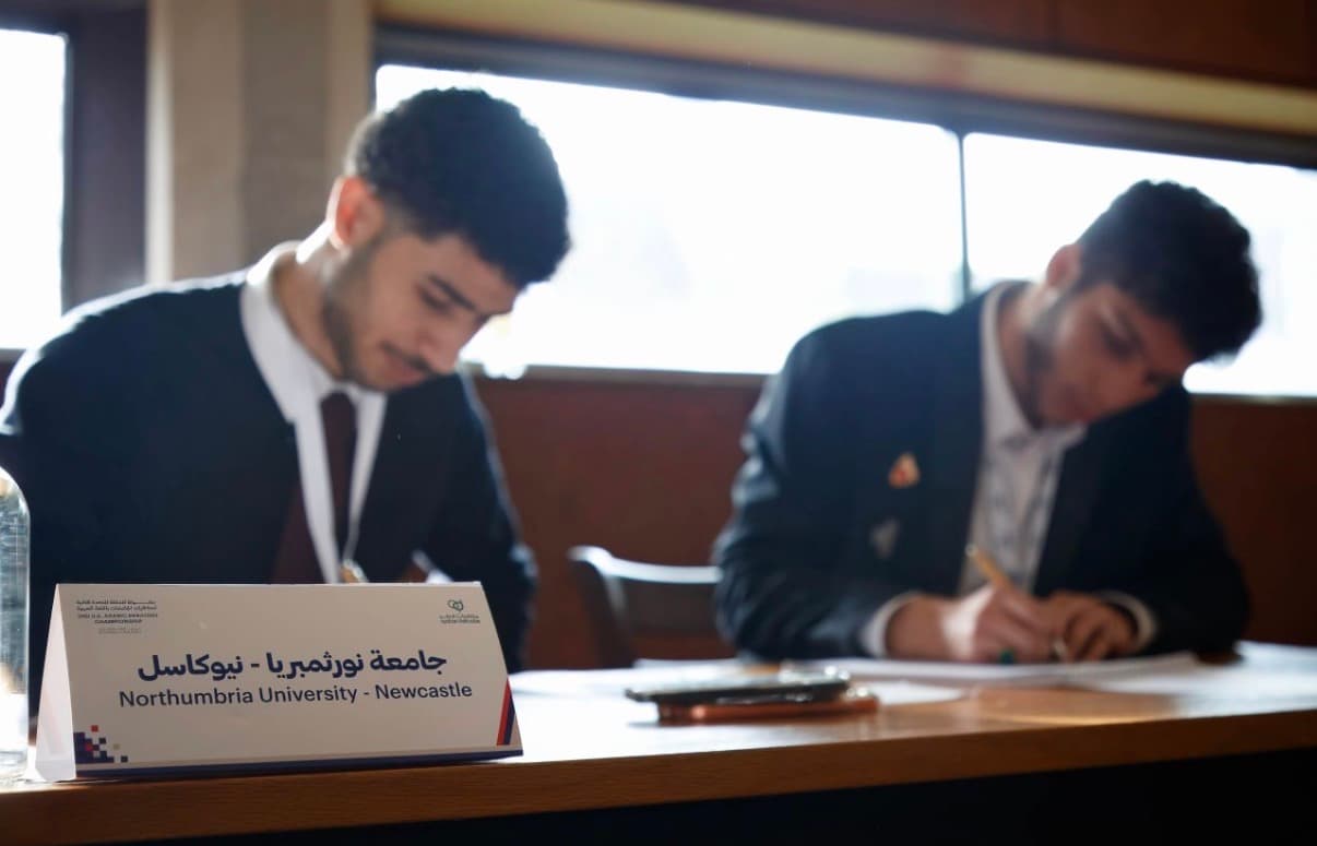 Northumbria University Newcastle nameplate beside debaters at the Oxford championship